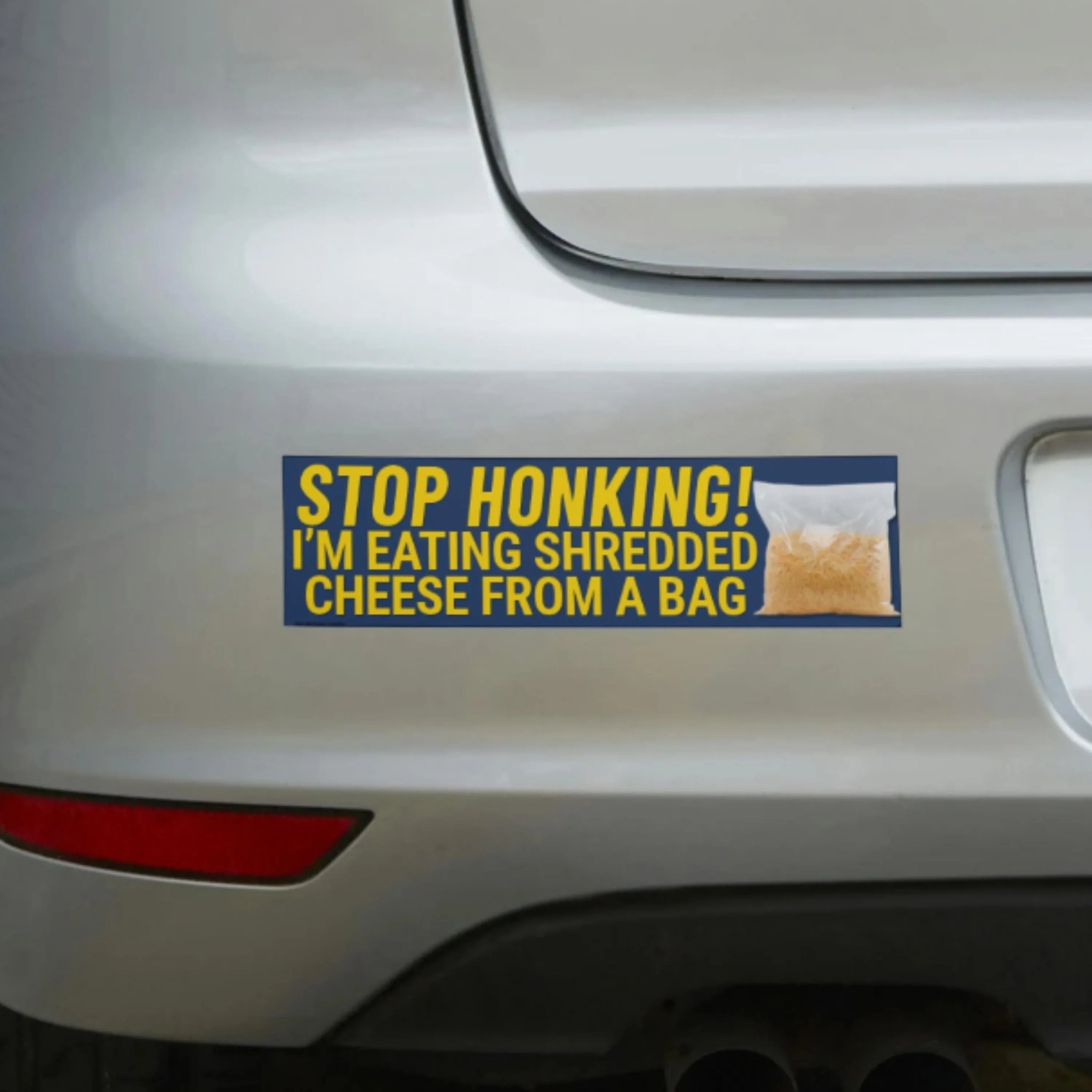 Funny bumper sticker: 'Stop Honking! I'm Eating Shredded Cheese From a Bag' on car rear.