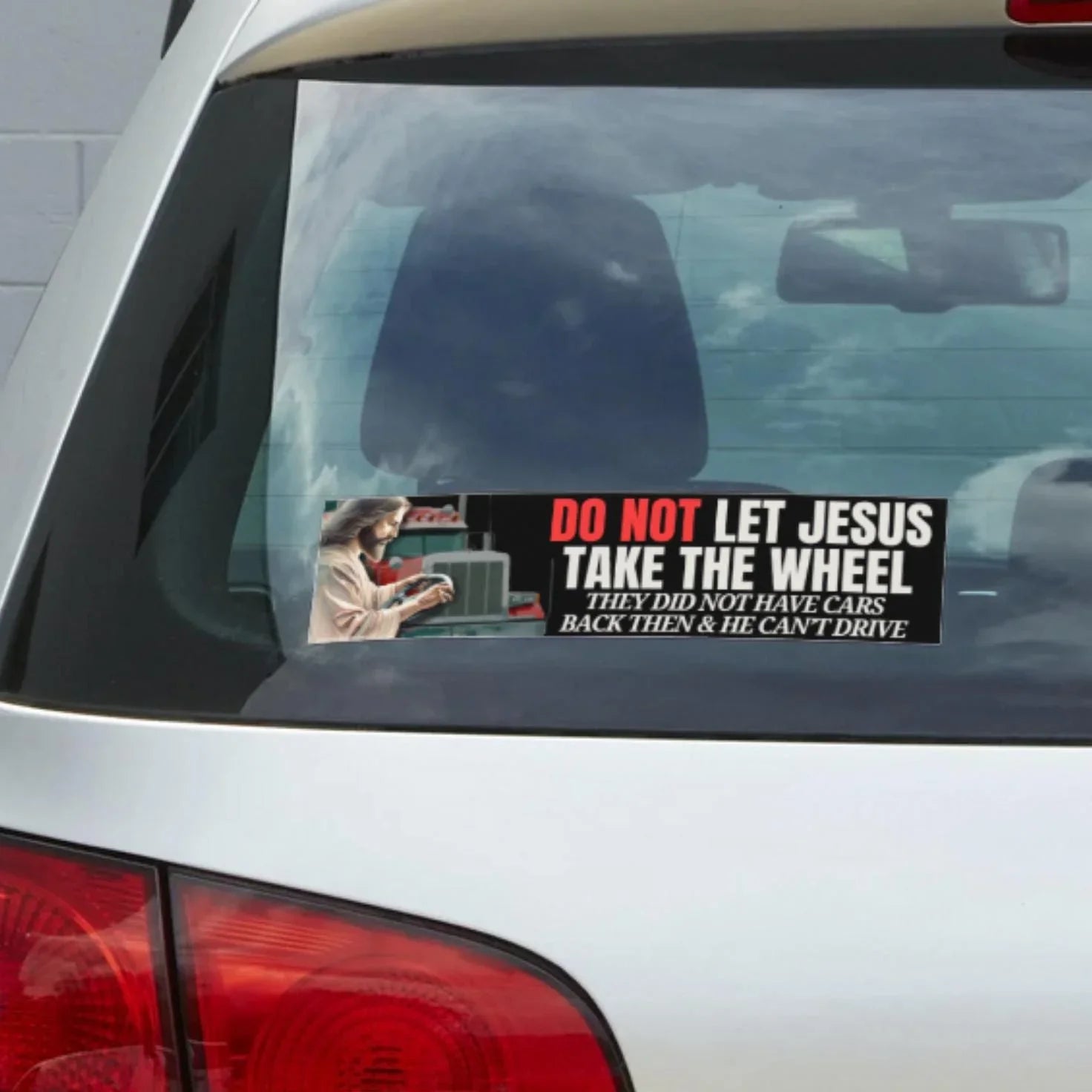 Funny bumper sticker on car window with text: Do Not Let Jesus Take The Wheel, featuring Jesus illustration.