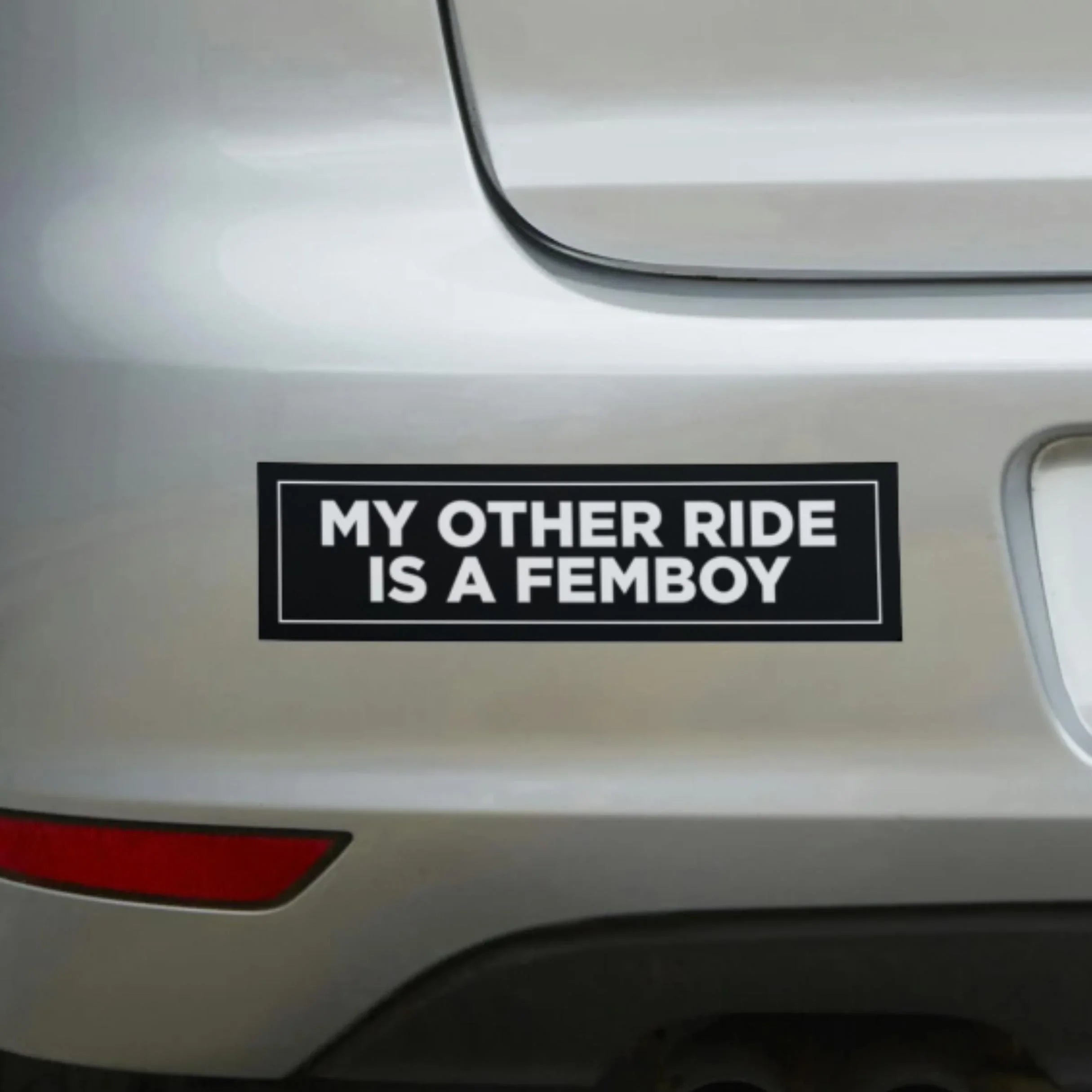 Funny black and white bumper sticker on car reading 'My other ride is a femboy'.