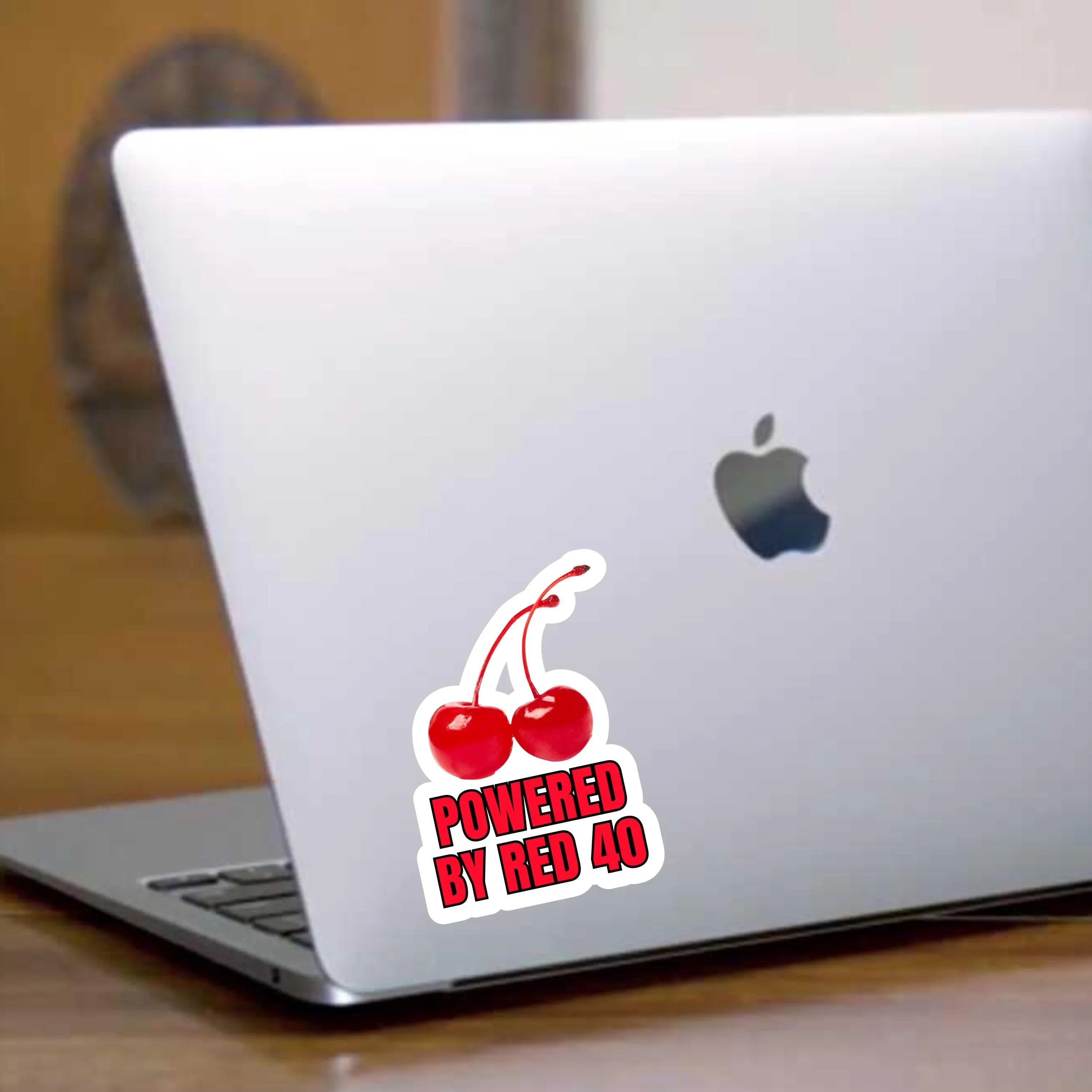 Powered by Red 40 cherry sticker on laptop, bold vinyl design