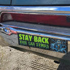 Stay Back This Car Stinks bumper sticker with skull design on chrome car bumper