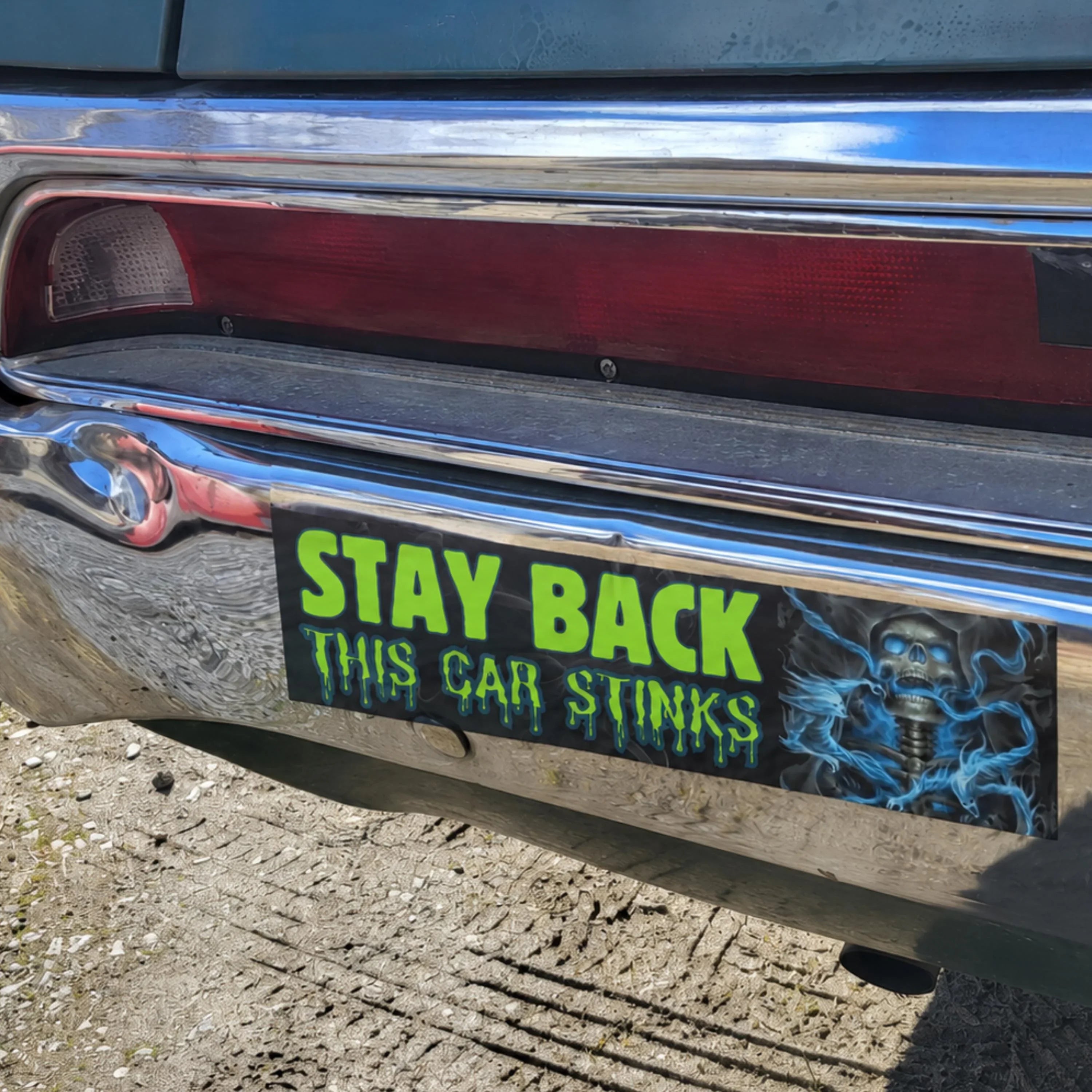 Stay Back This Car Stinks bumper sticker with skull design on chrome car bumper