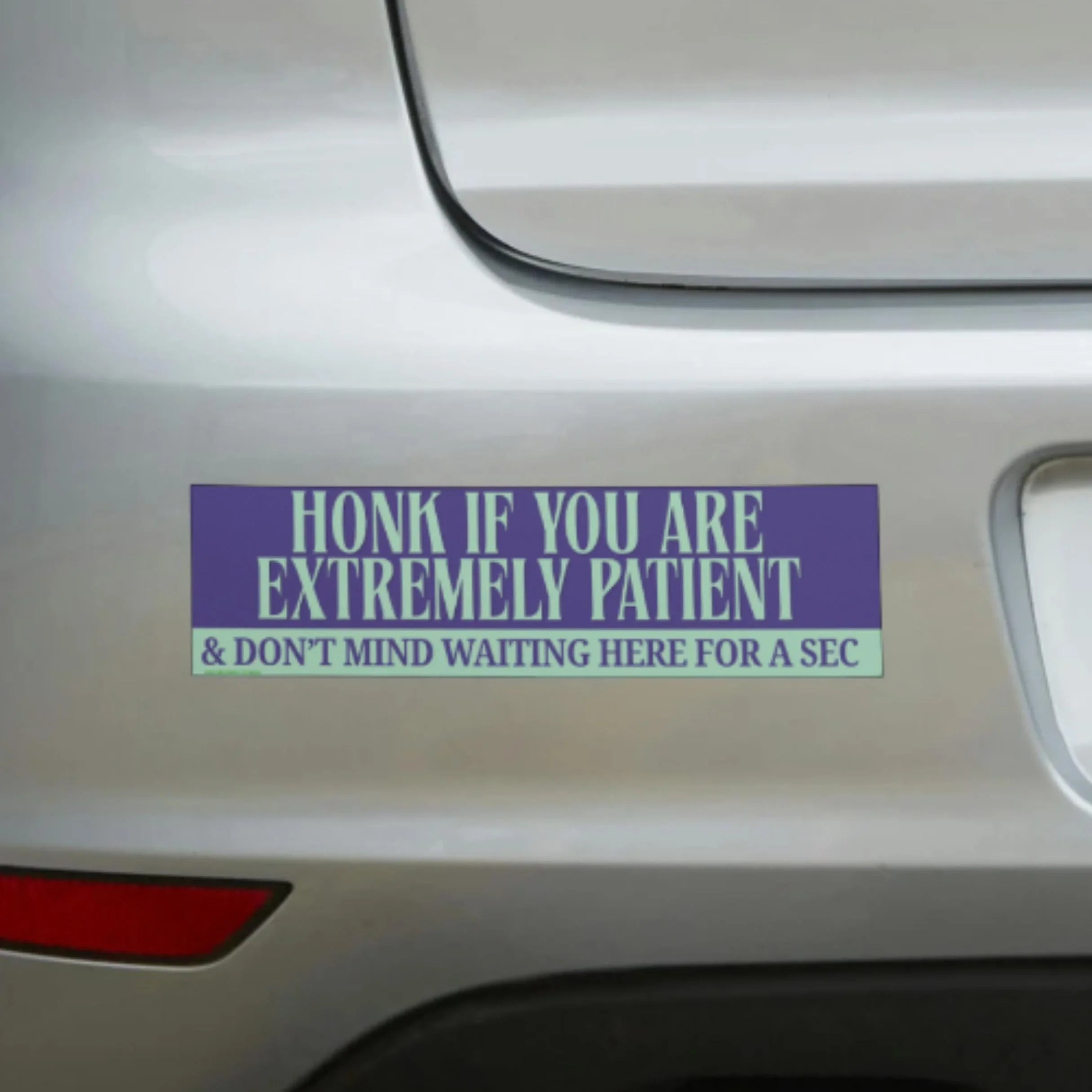 Purple bumper sticker reading 'Honk if you are extremely patient & don't mind waiting here for a sec' on car